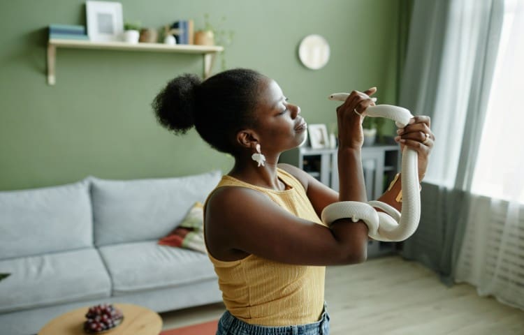 Woman looking at her pet snake in the living room